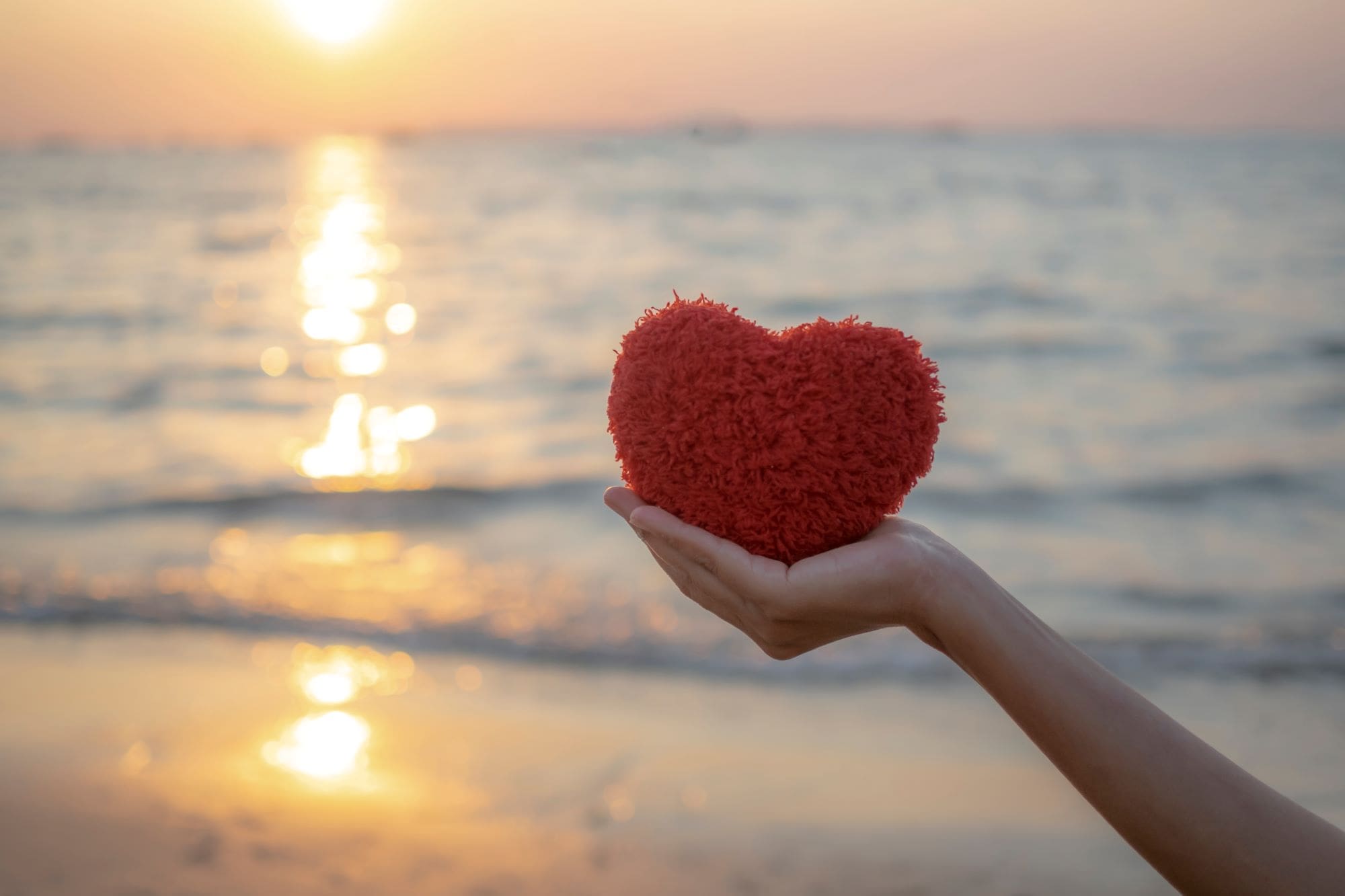 hand holding red heart on evening sunset background for valentine's day in fort walton beach